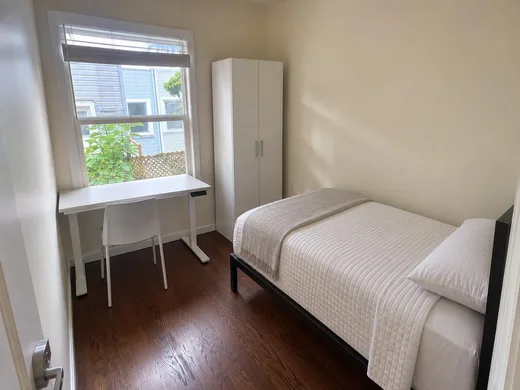 A room with the desk at the window and a full-height wardrobe