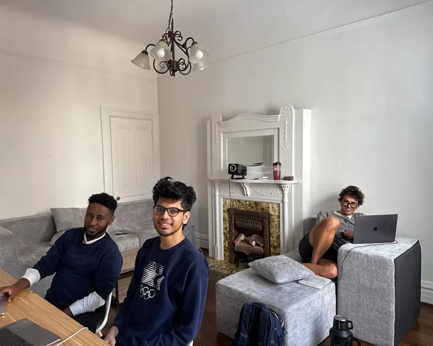 Residents coworking in a Foundry living room, laptops on the table and by the fireplace